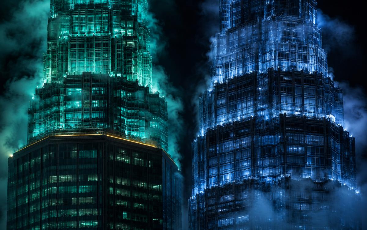 Two skyscraper crowns lit teal and blue facing off through storm clouds — two giants making the same bet